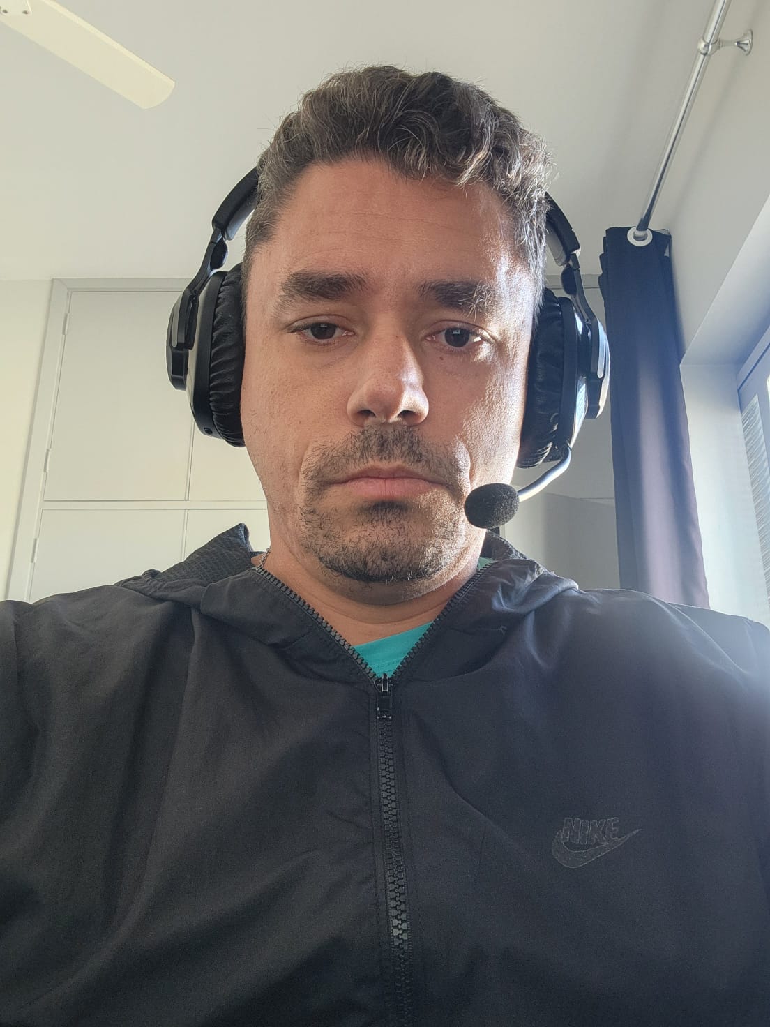 sobre mim, sou um homem branco de cabelo castanho curto, estou usando um fone de ouvido preto da JBL, estou usando uma blusa preta.